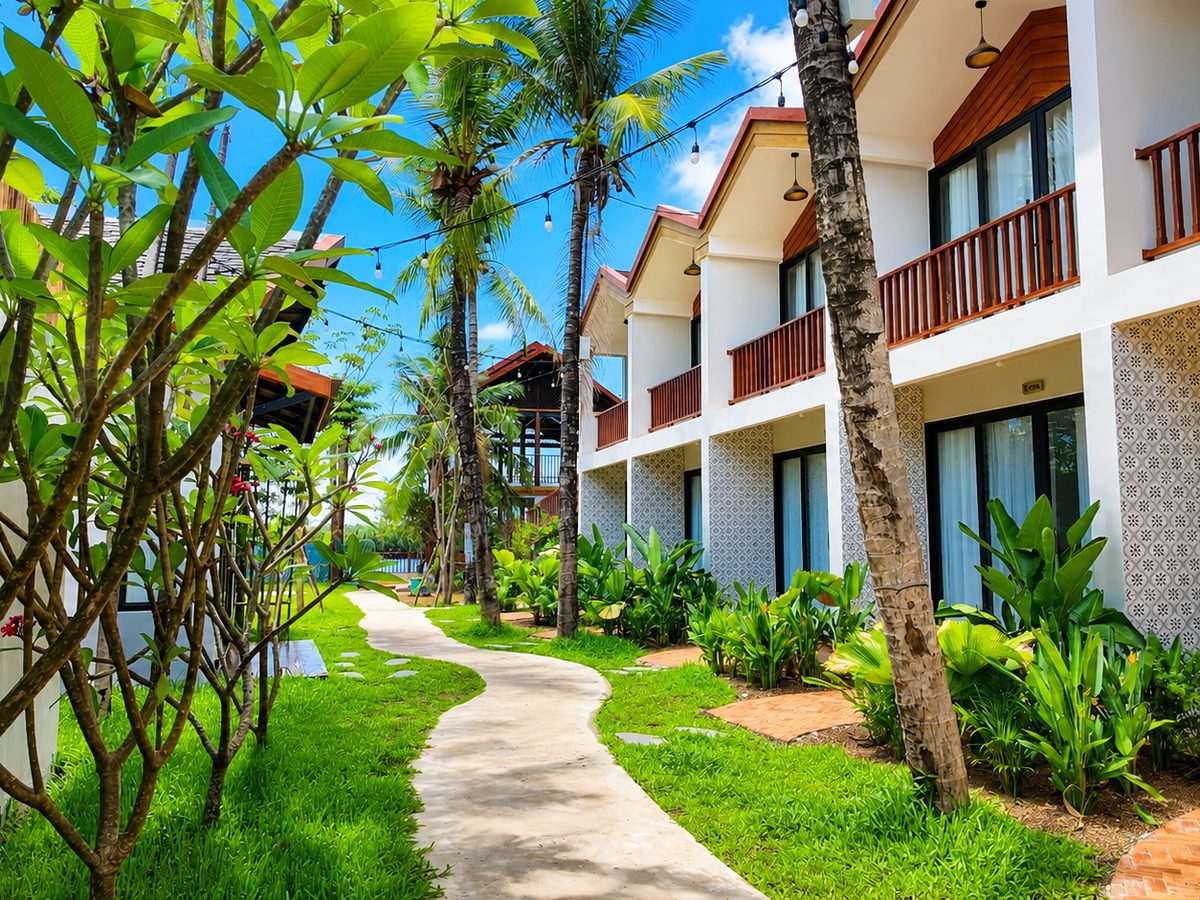 Upper-floor rooms with private balconies along a planted garden path