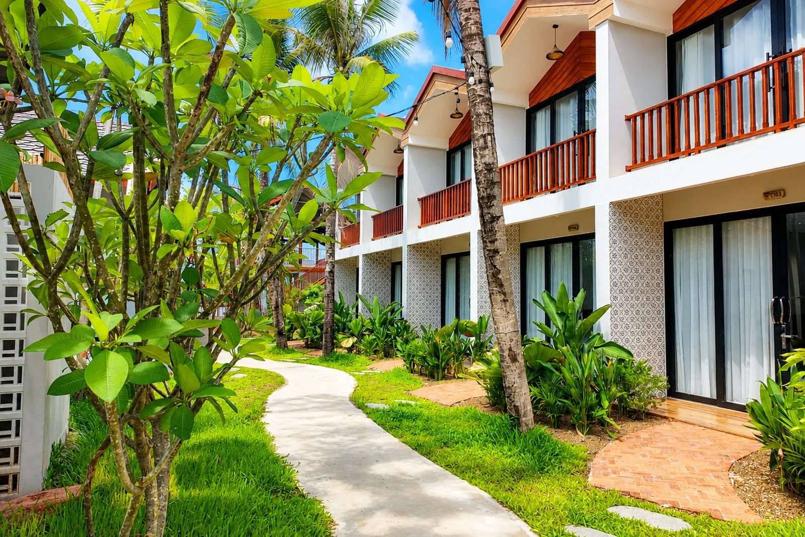 A frangipani-lined path running alongside the guest rooms